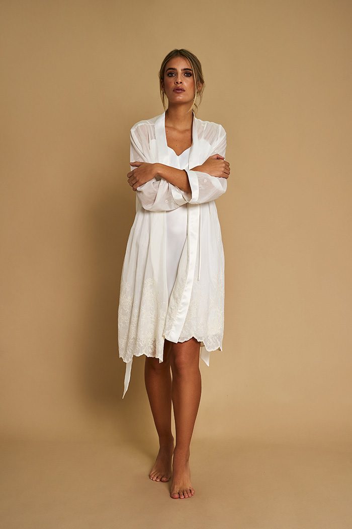 Alma bridal robe from the front, arms crossed, with scalloped hem