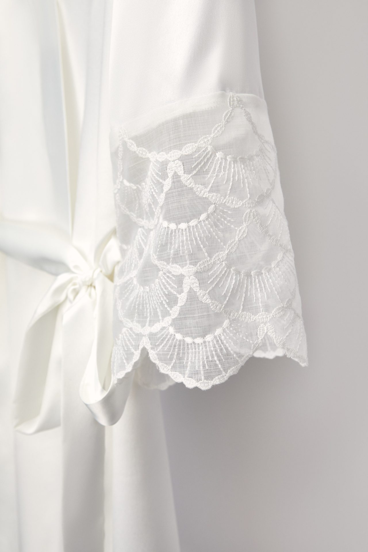Sleeve of the Lola bridal robe with scalloped lace and satin bow
