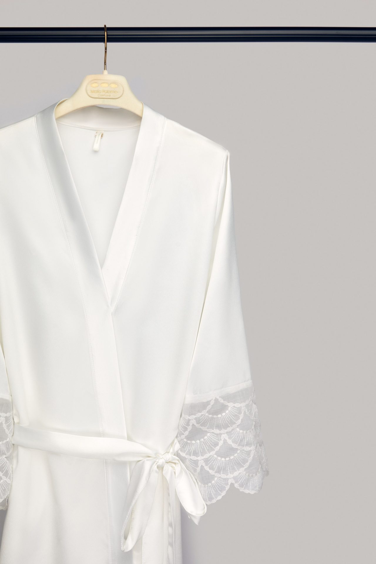 Lola satin bridal robe with lace sleeves on its hanger