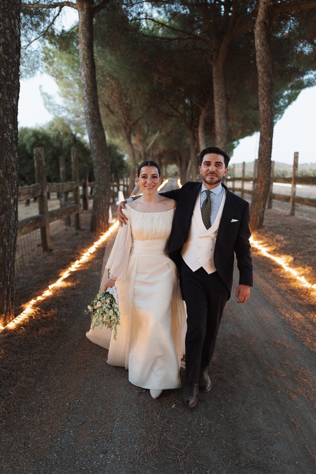 Inmaculada y Jesús, recién casados, caminan abrazados por un camino iluminado de la finca donde celebraron su boda