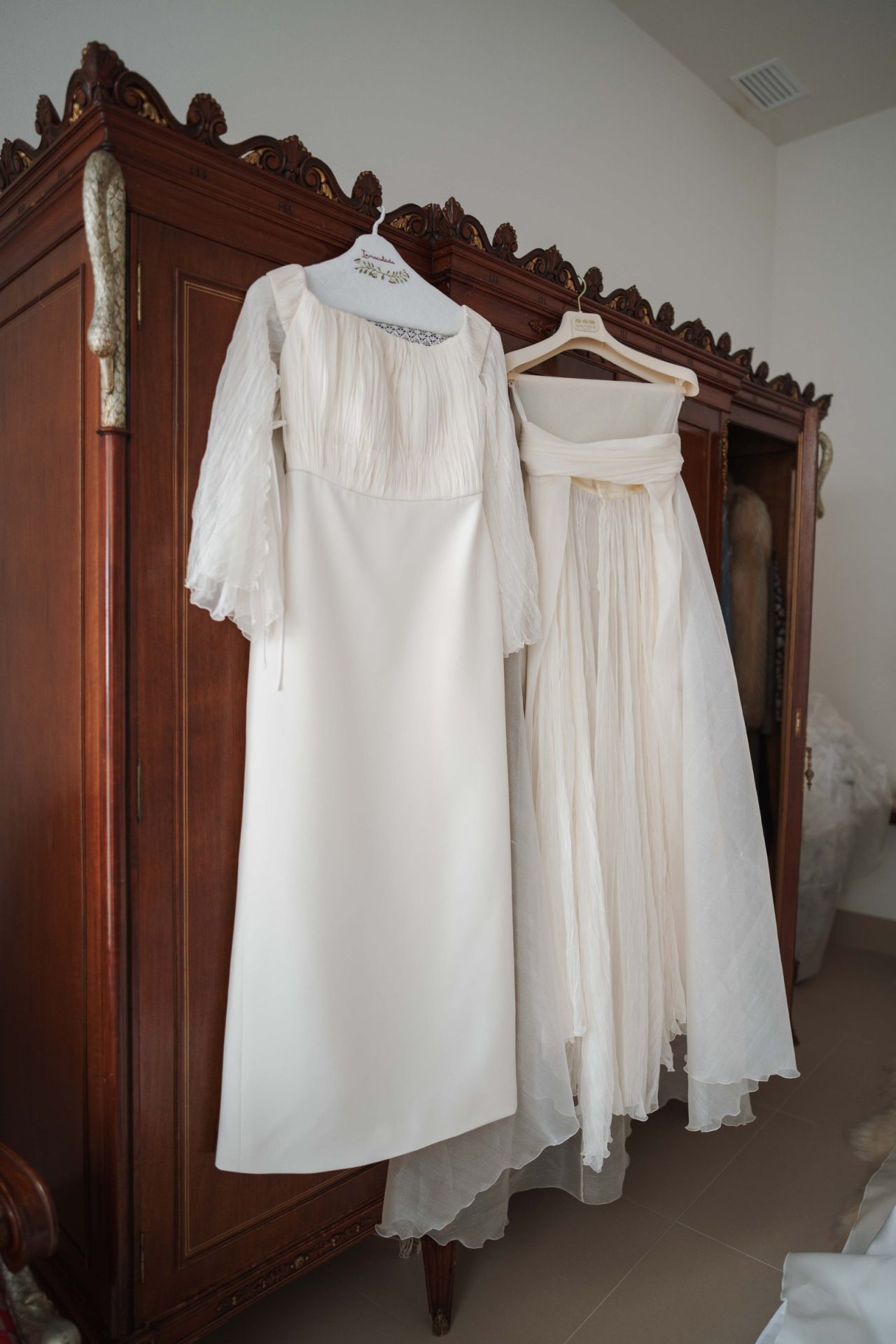 Las piezas del vestido de novia desmontable de Inmaculada colgadas en el armario antes de vestirse: el vestido con mangas de seda y la sobrefalda